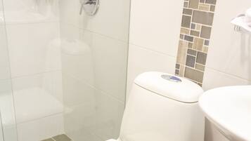 A modern bathroom with a toilet, a shower enclosure, and a toilet paper holder.
