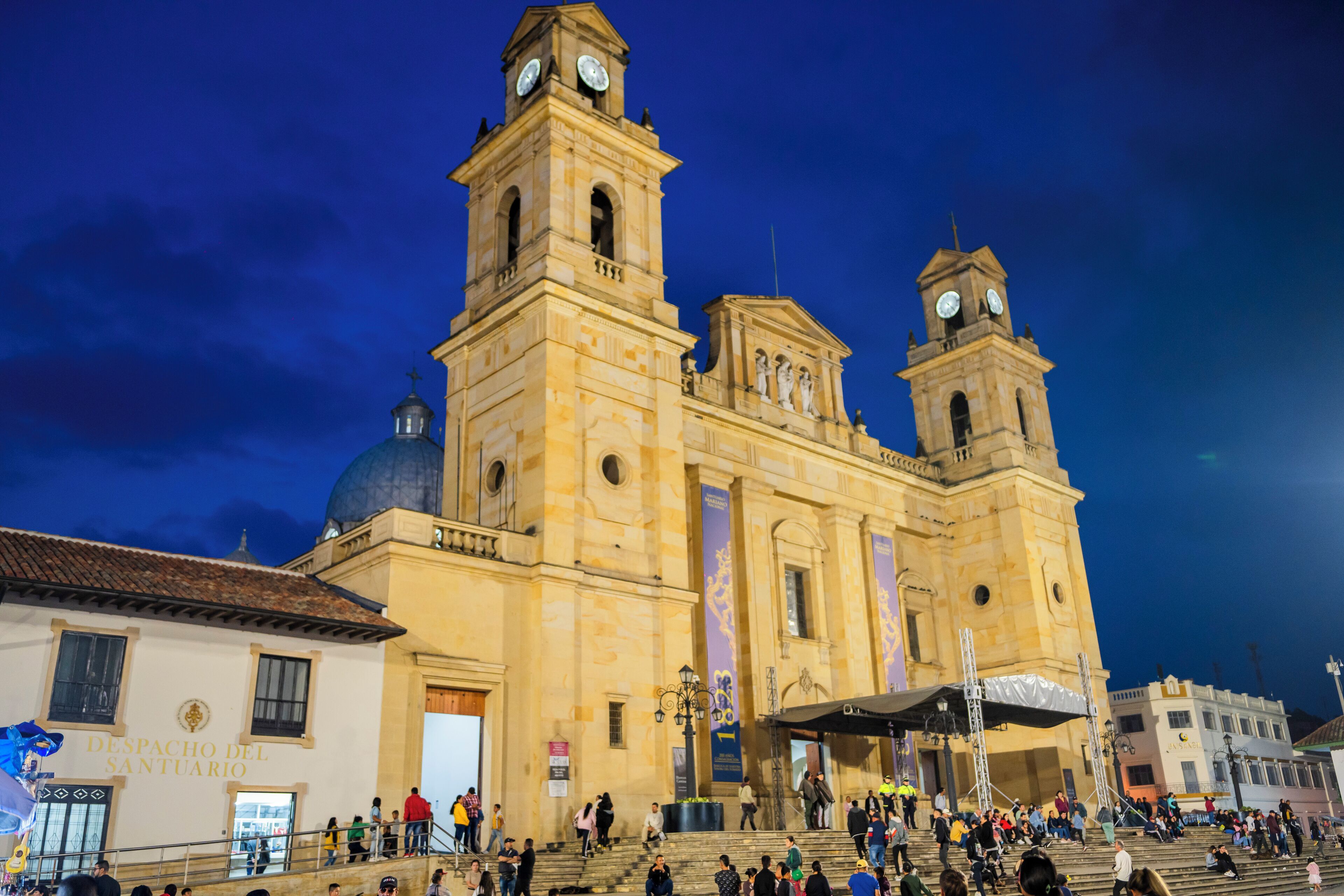 A historic building with two prominent towers and a dome, featuring a large open plaza in front.