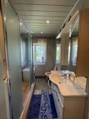 A modern bathroom with a double sink, a toilet, a washing machine, and a shower. - Apartment Kitzbuhel near Ski Slopes (Kitzbühel)