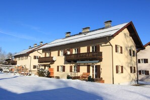 Un bâtiment à deux étages doté d’un balcon, d’une terrasse en bois et d’un sol recouvert de neige.