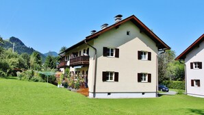A two-story building with a balcony, a garden in the foreground, and mountains in the background. - Apartment Kitzbuhel near Ski Slopes (Kitzbühel)
