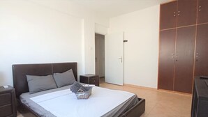 A bedroom with a bed, nightstands, a wardrobe, and a door. - Umm Haram whole apartment · 5 min walk to the Beach! NETFLIX & fast Internet (Larnaca)