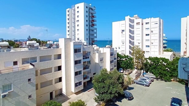 A residential area with multi-story buildings, a parking lot, and a view of the sea. - Umm Haram whole apartment · 5 min walk to the Beach! NETFLIX & fast Internet (Larnaca)