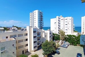 A residential area with multi-story buildings, a parking lot, and a view of the sea.