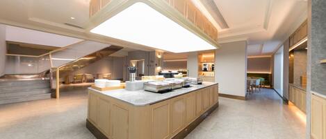 A modern kitchen with a central island, built-in appliances, and a staircase leading to an upper level.