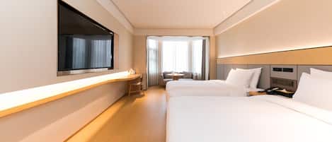 Habitación de hotel con dos camas, un escritorio, una silla, un televisor y una ventana.