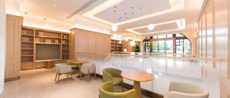 A modern interior with a seating area, bookshelves, and a view through a glass wall.