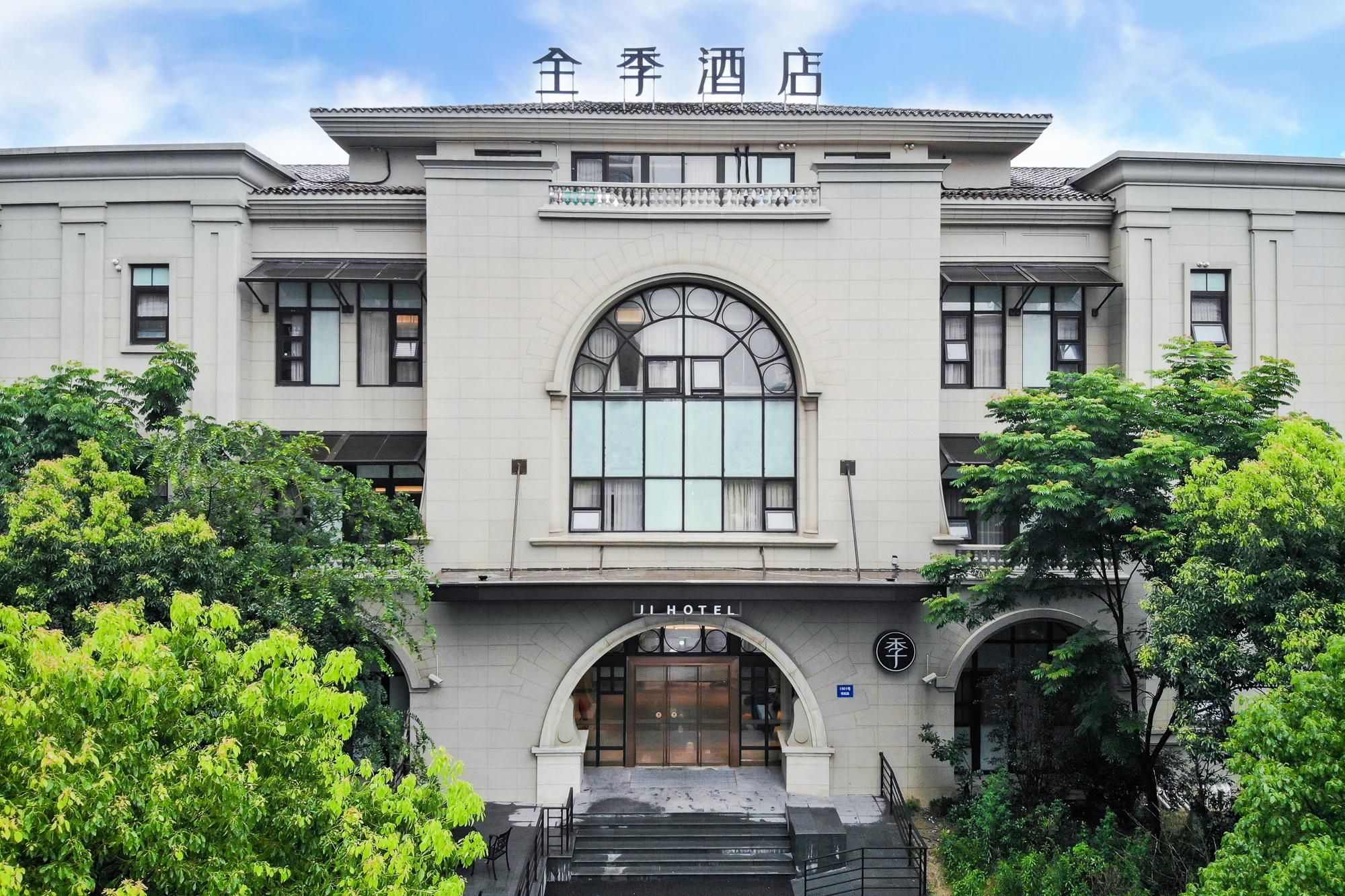 Un hotel de estilo arquitectónico tradicional, con una entrada arqueada destacada y un gran ventanal de diseño calado.