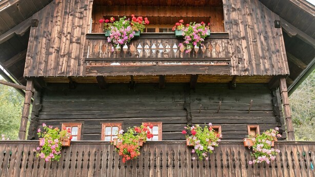 Een houten chalet met een balkon versierd met bloembakken.