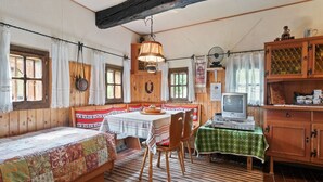 Een knus vertrek met houten wanden, een bed met een kleurrijke quilt, een eettafel met stoelen, een televisie en een kast met keukengerei.