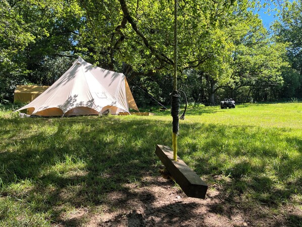 Una tenda montata in un'area erbosa, con alberi sullo sfondo.