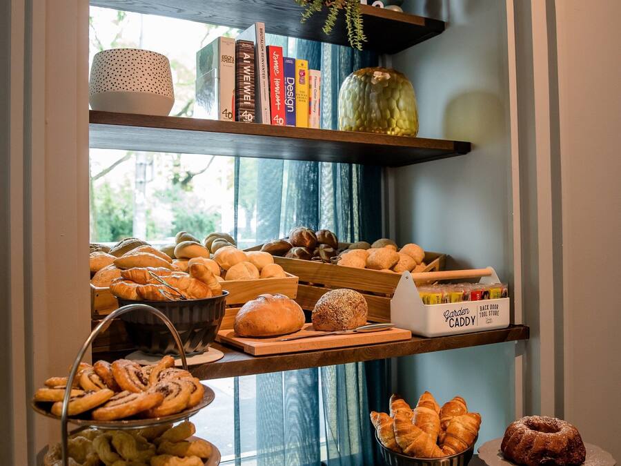 Un bufé de desayuno con pasteles, libros y objetos decorativos en estanterías.