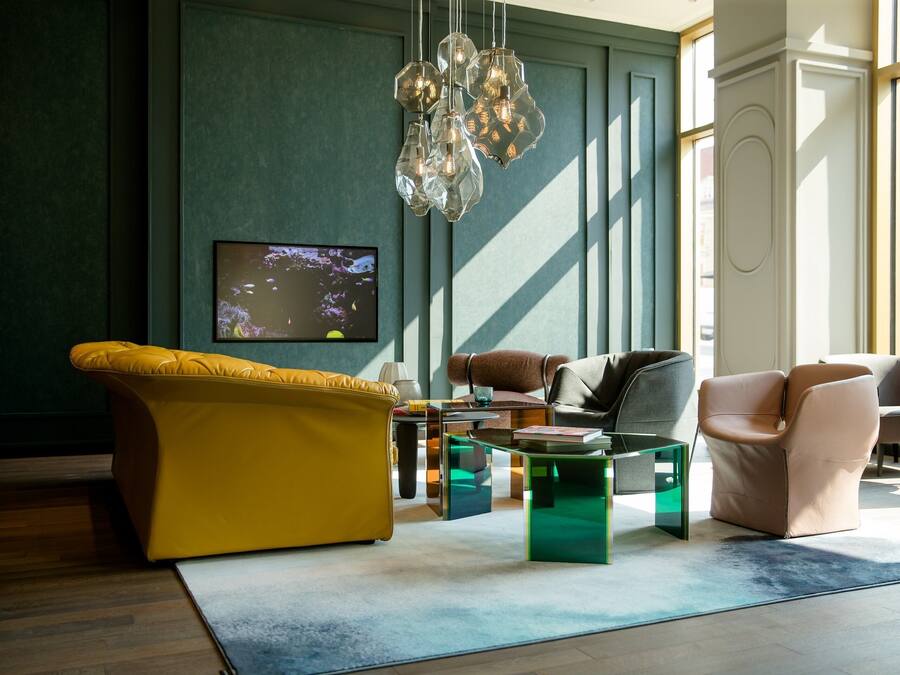 A modern living room with a yellow sofa, a brown leather chair, and a glass coffee table.