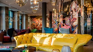 Eine moderne Hotelhalle mit einem gelben Ledersofa, zeitgenössischer Kunst und stimmungsvoller Beleuchtung.