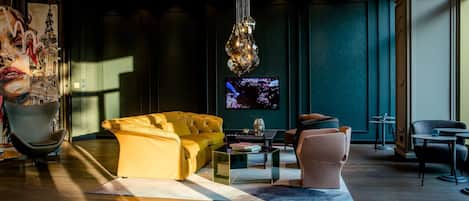 A modern living room with a yellow sofa, a glass coffee table, and a large abstract painting on the wall.