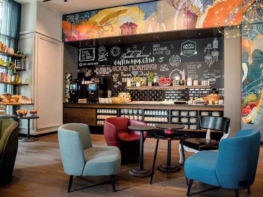 Interior de una cafetería con asientos, una barra y decoración en las paredes.