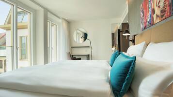 Hotelkamer met een groot bed, een bureau, een stoel, een ronde spiegel en een schilderij aan de muur.
