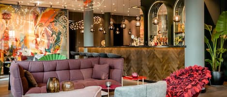 A modern interior with a plush seating area, a bar with a herringbone wood wall, and decorative lighting.
