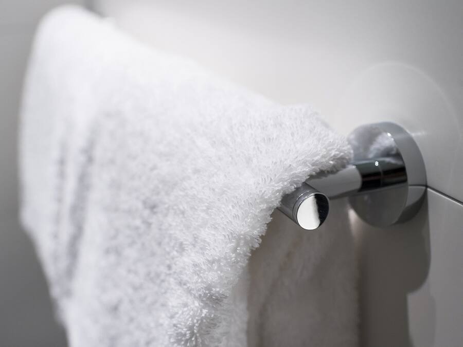 Una toalla blanca colgada en un toallero de cromo en un baño.