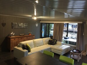 En moderne stue med en hvid hjørnesofa, et træskab og et spisebord.