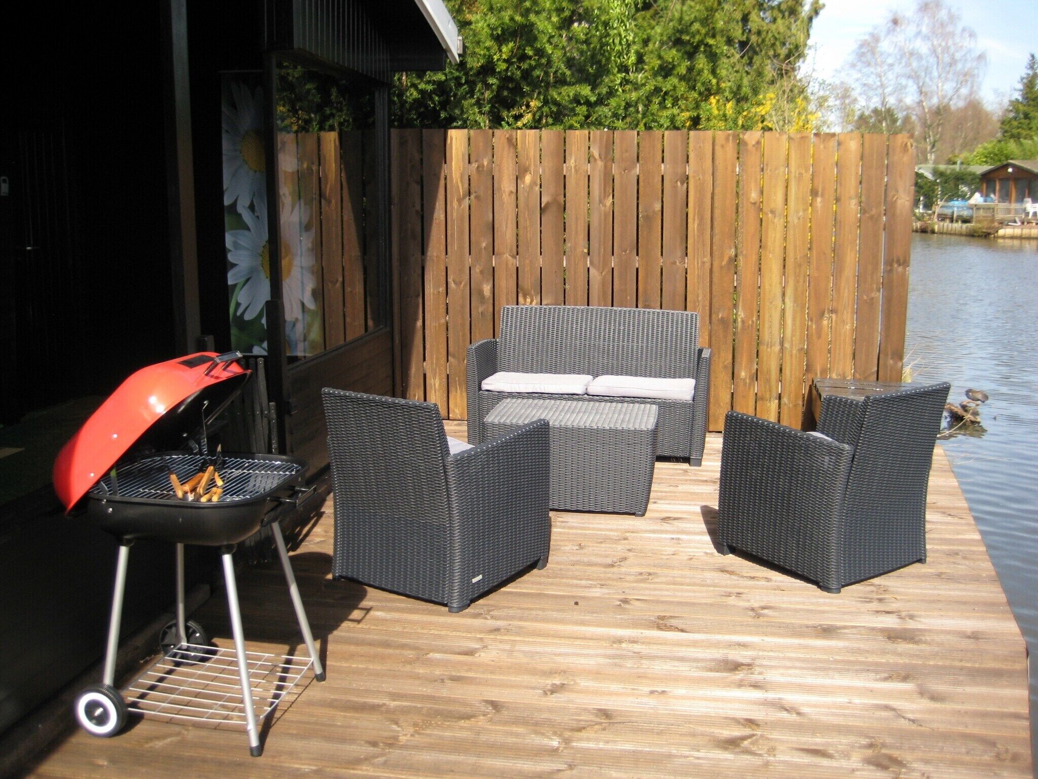 A wooden deck with wicker furniture and a barbecue grill.