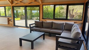 Un espacio habitable moderno y abierto con un conjunto de sofás, una mesa de centro y ventanas amplias con vistas a zonas verdes.