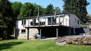 Een modern gebouw met twee verdiepingen, een balkon en een overdekte zithoek buiten.