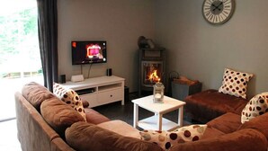 Een gezellige woonkamer met een open haard, een televisie en een klok aan de muur.