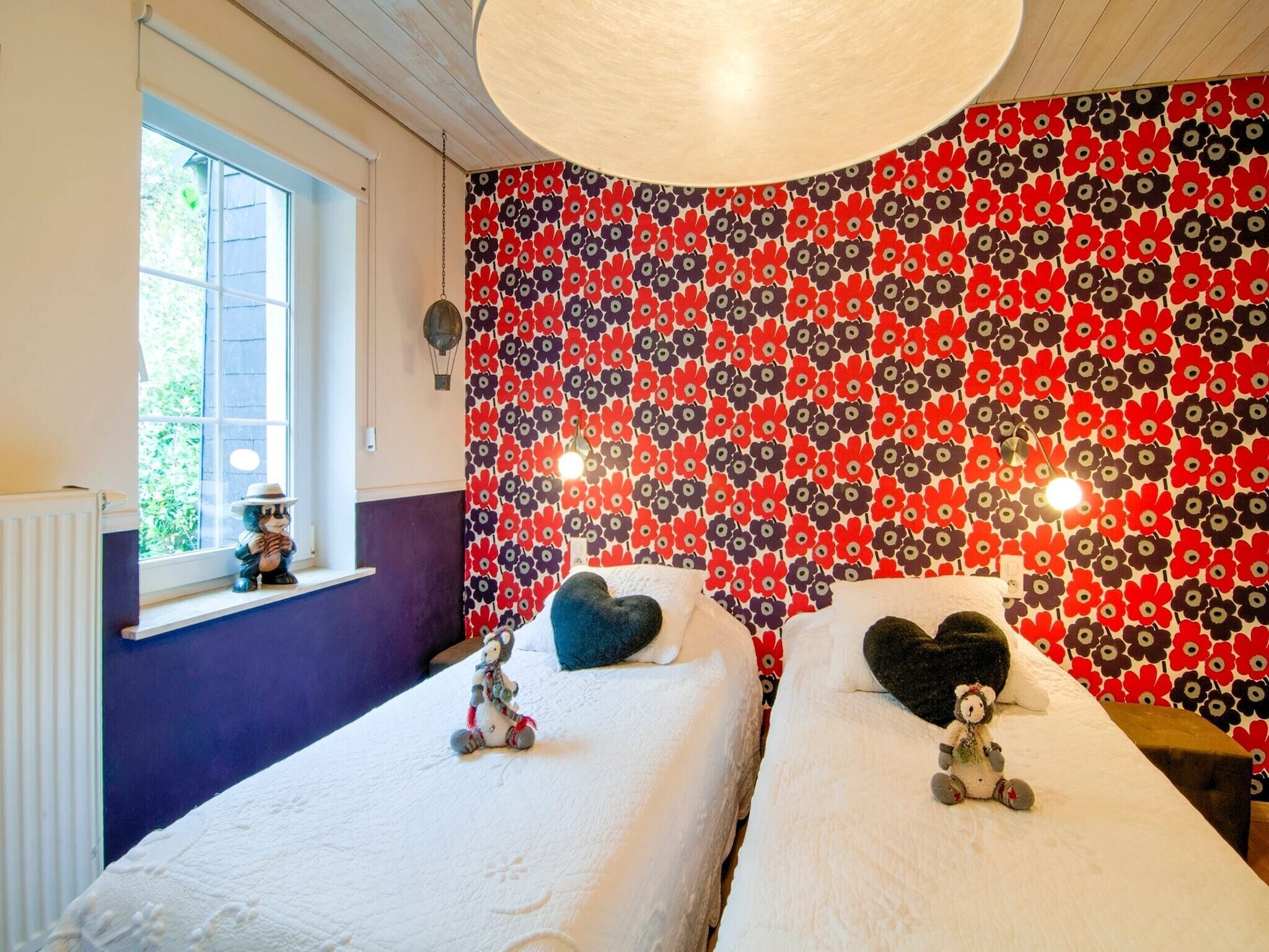 Un dormitorio con dos camas, una ventana con vistas y una pared con diseño floral.
