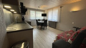 Ein kompakter Wohnraum mit Küchenzeile, Essbereich und einem Bett.