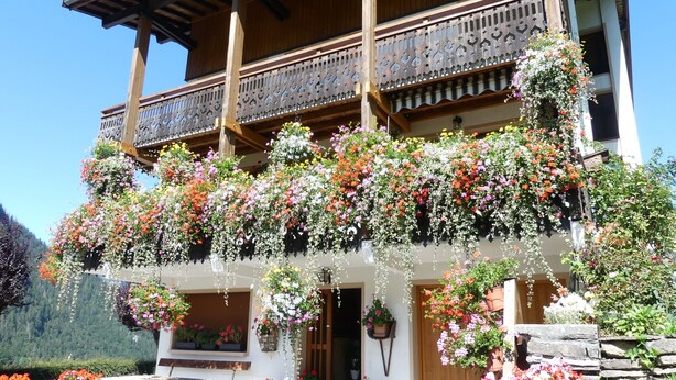Ein traditionelles Holzhaus mit einem Balkon, der mit hängenden Blumenkästen geschmückt ist.