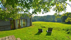 Une cabane en bois avec deux fauteuils confortables, située dans un champ verdoyant.