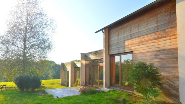 Une maison moderne dotée de grandes fenêtres et d’une pelouse bien entretenue.