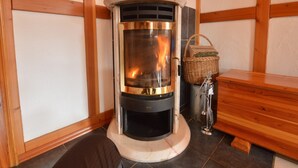 A wood-burning stove in a corner with a bench and a basket. - Holiday home in Butgenbach near the Lake (Bütgenbach)
