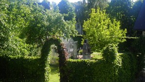A garden with a statue, a hedge, and a building in the background. - Holiday home in Butgenbach near the Lake (Bütgenbach)