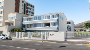 A modern building with a nameplate 'VREDENHOF' on the facade, featuring a multi-story structure with large windows and a gated entrance. - Spacious, Light and Bright on the Beachfront!!! (Cape Town)