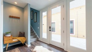A hallway with a wooden bench, a rug, and a staircase leading to a door.