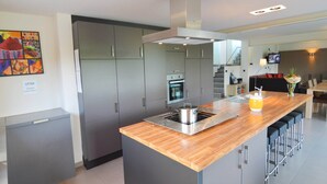 Una cocina moderna con gabinetes grises, una isla de madera y un horno empotrado.