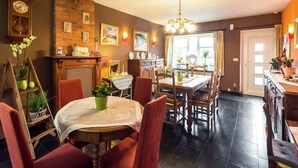 A dining area with a round table, chairs, a chandelier, and a brick wall with framed pictures. - Scenic Retreat in Gimnée (Gimnée)