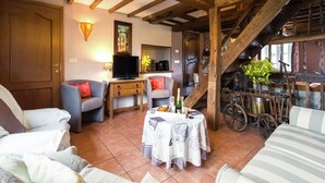 A cozy living room with a wooden ceiling, a television, a table with drinks, and a staircase. - Scenic Retreat in Gimnée (Gimnée)