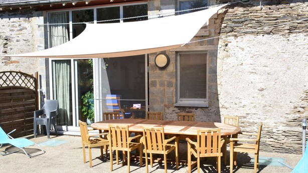 A patio with a wooden table and chairs, a white awning, and a stone wall. - Nature Escape in Martelange (Martelange (radelange))