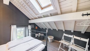 A bedroom with a skylight, a bed, a chair, and a small table. - Charming Home in Ardennes (Petit-Thier)