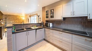 A modern kitchen with grey cabinets, a black countertop, and a stone backsplash. - Charming Home in Ardennes (Petit-Thier)