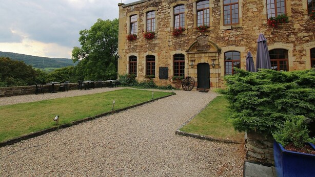 A stone building with a gravel driveway, outdoor seating, and a view of the countryside. - Rustic Charm, Modern Comfort (Latour)