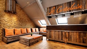 A cozy, rustic interior with a stone wall, wooden bench seating, and a bar area.