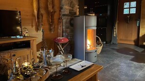 Ein gemütliches Zimmer mit Steinwand, Kamin, Fernseher und einem Holztisch mit Dekoration.