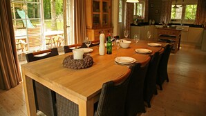 A dining area with a wooden table set for six, surrounded by wicker chairs. A cabinet with glass doors is visible in the background. - Countryside Chalet in 	Bomal sur Ourthe with Sauna, Balcony (Bomal sur Ourthe)