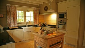 A kitchen with wooden cabinets, a wooden island, a sink, a microwave, and an oven. - Countryside Chalet in 	Bomal sur Ourthe with Sauna, Balcony (Bomal sur Ourthe)