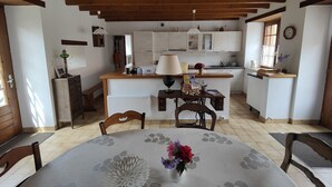 A kitchen with white cabinets, a wooden ceiling, and a dining area with a table set for two.