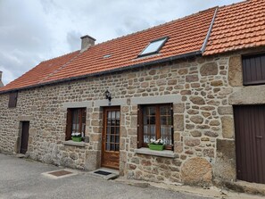 Ein Gebäude aus Stein mit rotem Ziegeldach, Holztüren und Fenstern mit Blumenkästen.